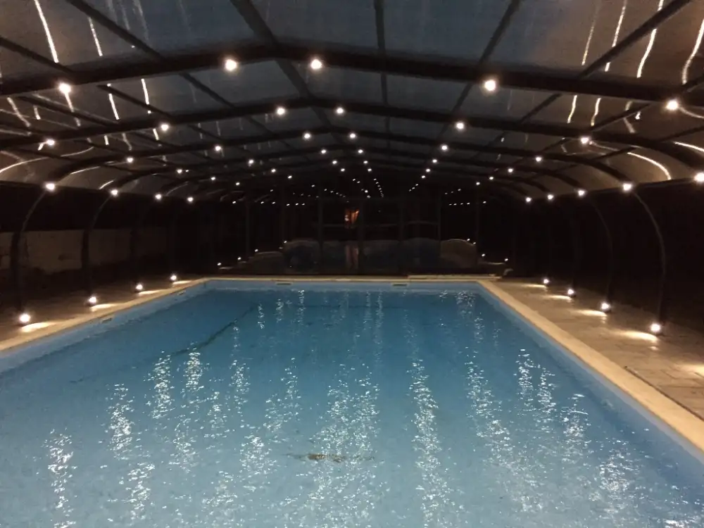 Piscine intérieure éclairée sous structure couverte la nuit