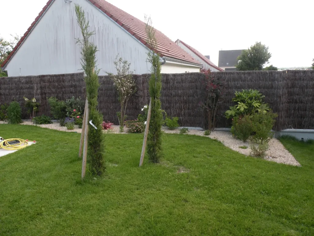 Jardin avec pelouse et jeunes arbres tuteurés