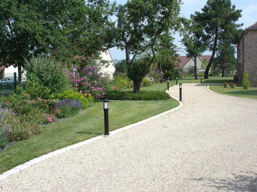 Allée gravillonnée bordée de jardin fleuri et lampadaires