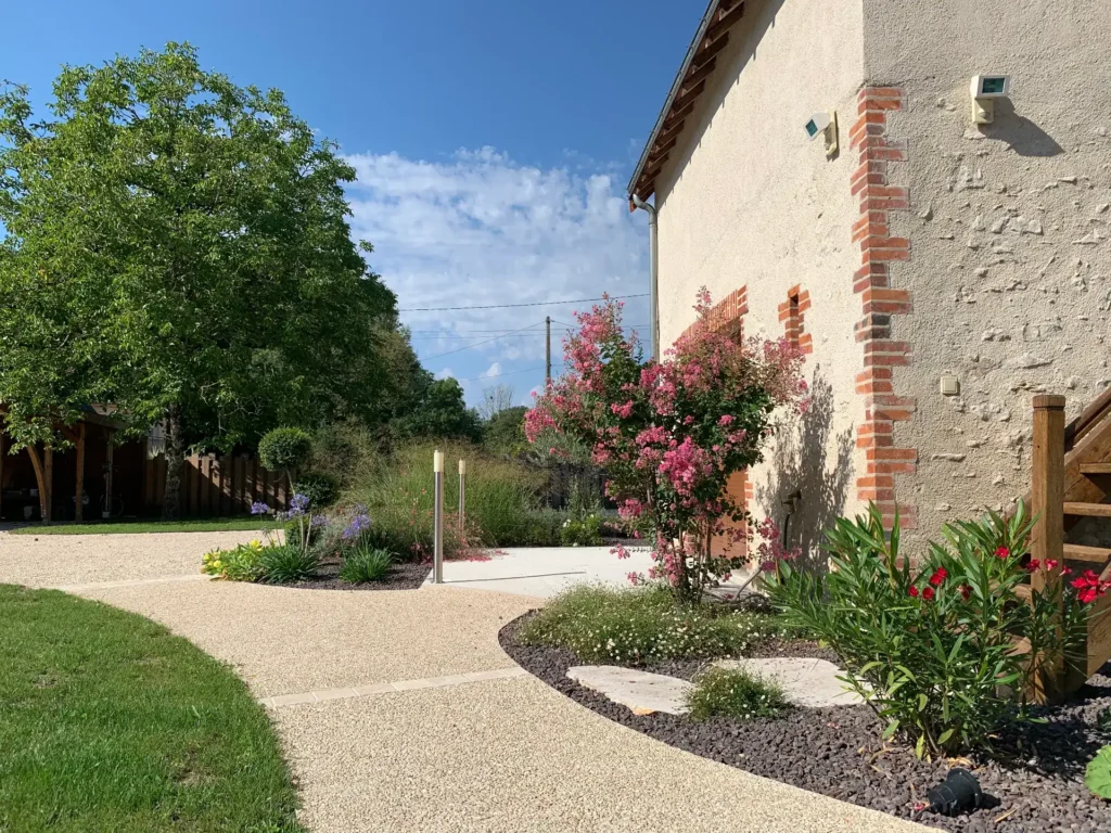 Jardin paysager avec maison en briques et fleurs roses