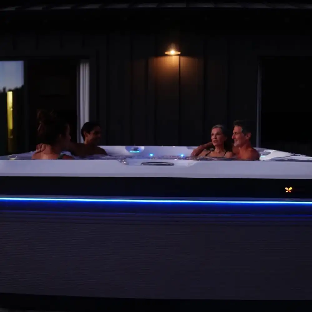 Quatre adultes dans un jacuzzi extérieur nocturne