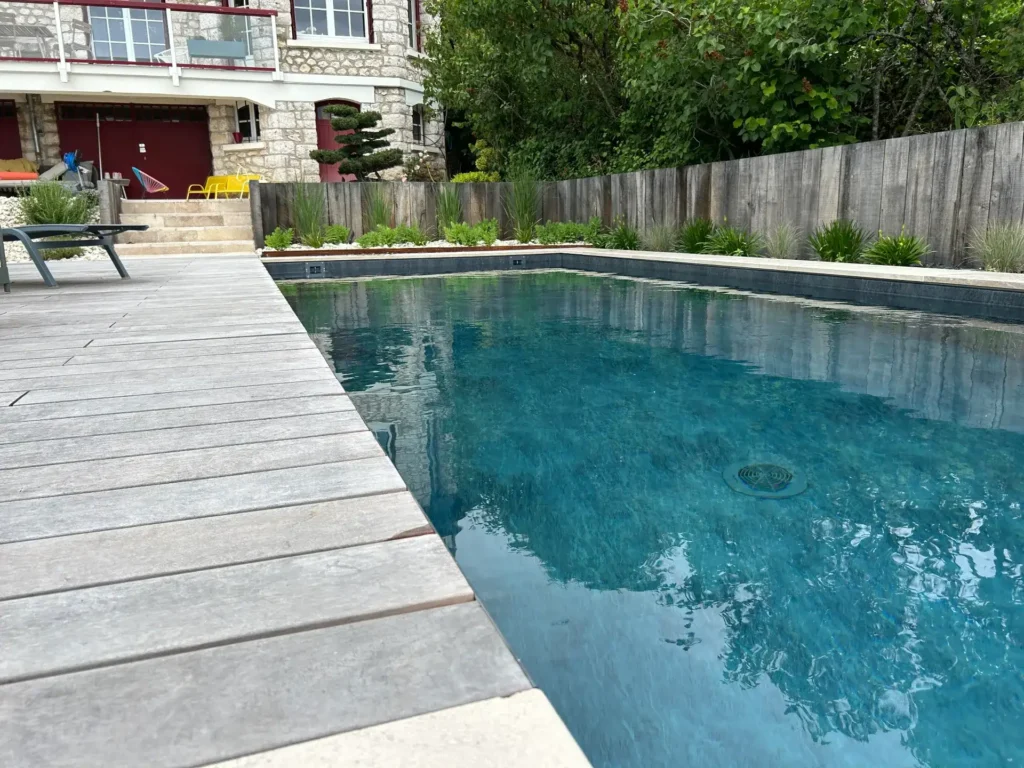 Piscine moderne avec terrasse en bois et jardin